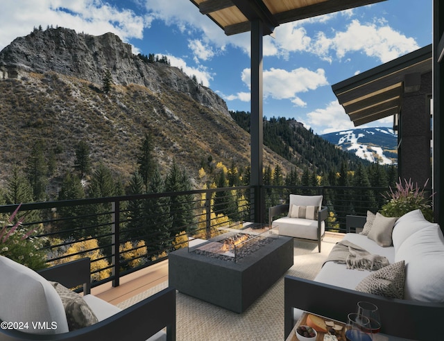 view of patio / terrace featuring a balcony, a mountain view, a view of trees, and an outdoor living space with a fire pit