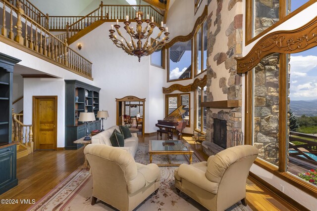 living room featuring hardwood / wood-style flooring, a fireplace, a chandelier, and a high ceiling