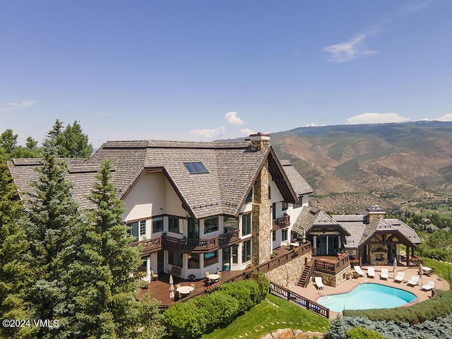 rear view of property featuring a mountain view, a patio area, and a lawn