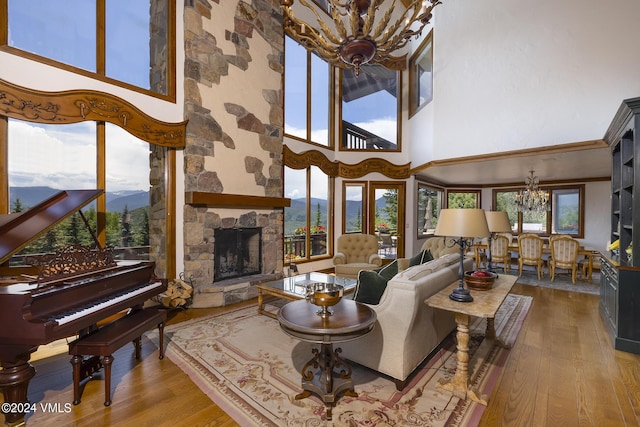 living room featuring a high ceiling, a fireplace, an inviting chandelier, and light hardwood / wood-style flooring