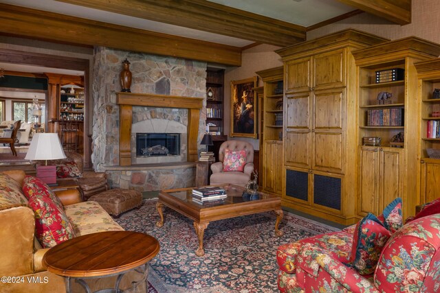 living room with a stone fireplace and beamed ceiling