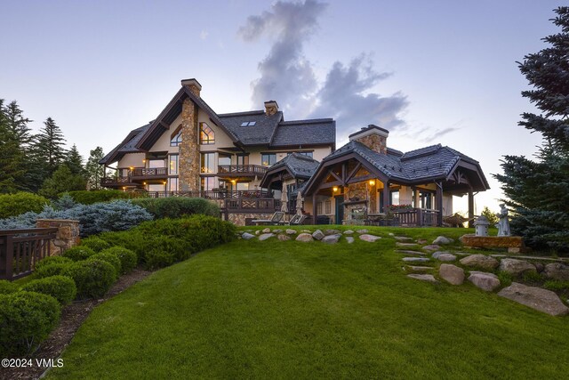 back house at dusk featuring a lawn