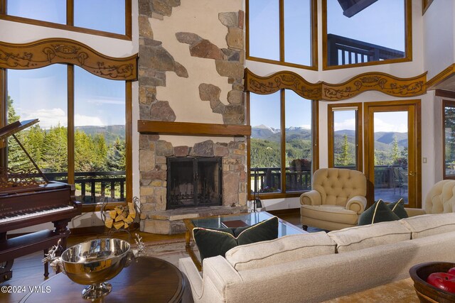 living room with a high ceiling, a stone fireplace, and a mountain view