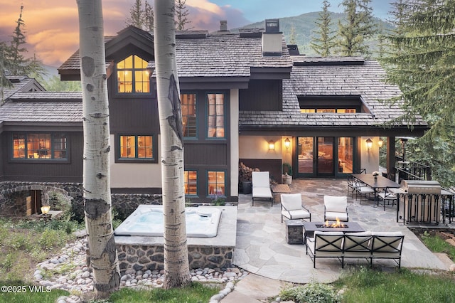416 Forest Rd Unit A, Vail, CO 81657 - back of property at dusk featuring an outdoor living space with a fire pit, a patio area, a chimney, and stone siding