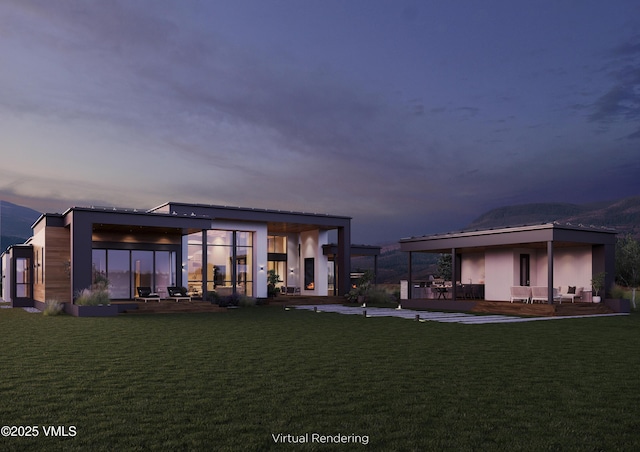 back house at dusk with a patio and a yard