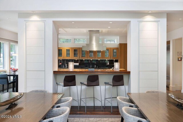 kitchen featuring hardwood / wood-style flooring, island range hood, and backsplash