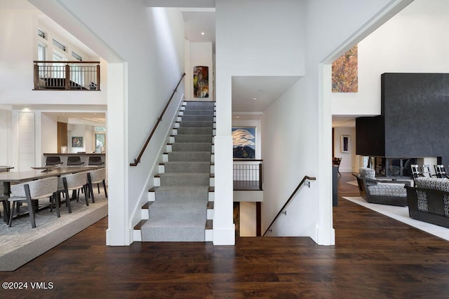 stairway with a towering ceiling and hardwood / wood-style floors