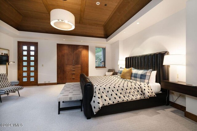 bedroom with wood ceiling, light colored carpet, and a raised ceiling