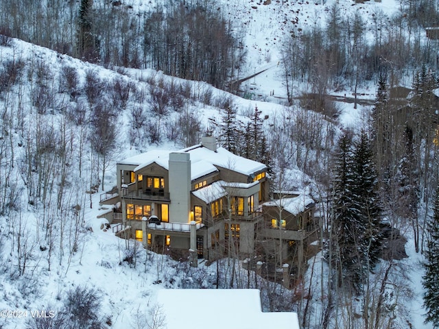 snow covered back of property featuring a balcony