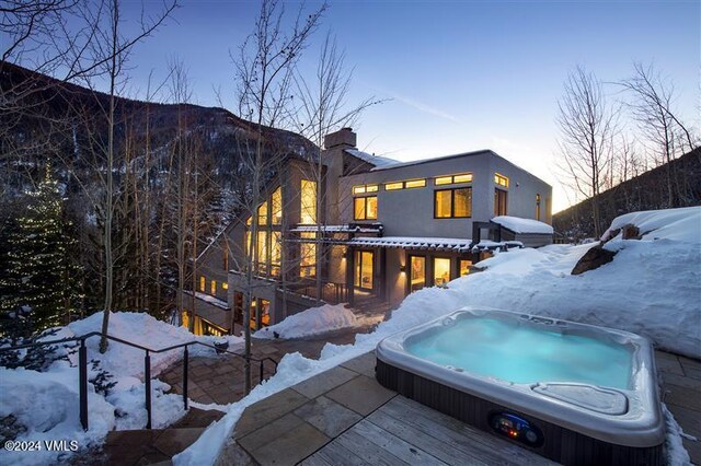 snow covered rear of property with a wooden deck