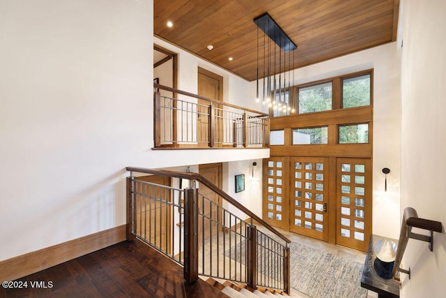 staircase featuring hardwood / wood-style floors, a high ceiling, and wooden ceiling