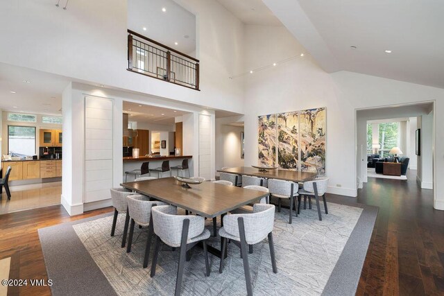 dining room featuring dark wood-type flooring and a towering ceiling