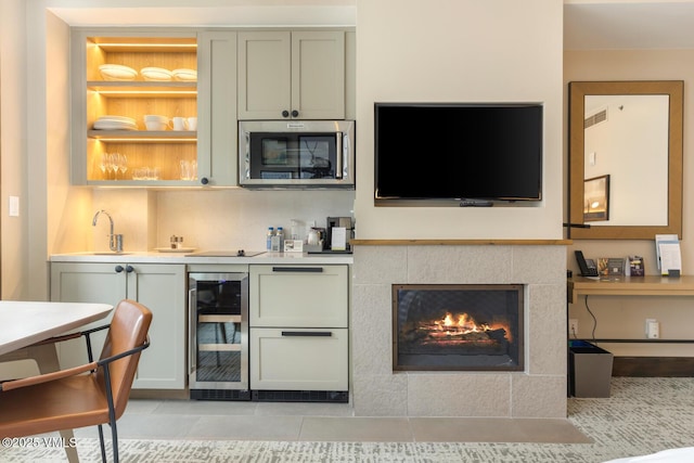 bar featuring wine cooler, a fireplace, visible vents, wet bar, and stainless steel microwave