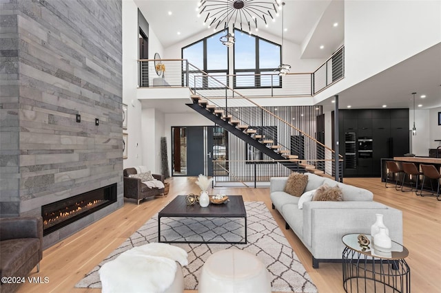 living room with a high ceiling, a tile fireplace, and light hardwood / wood-style flooring