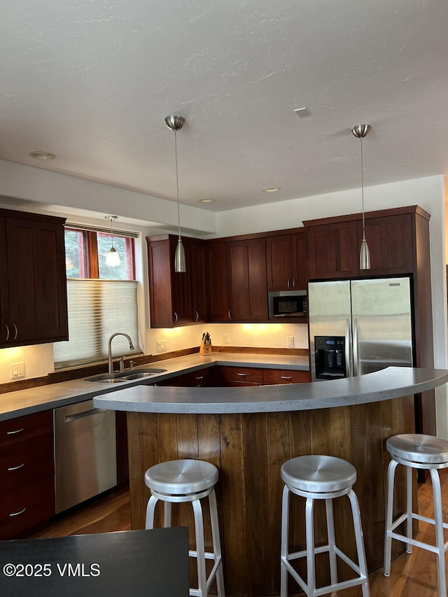 3105 Bellflower Dr, Vail, CO 81657 - kitchen featuring a kitchen breakfast bar, appliances with stainless steel finishes, a sink, and decorative light fixtures