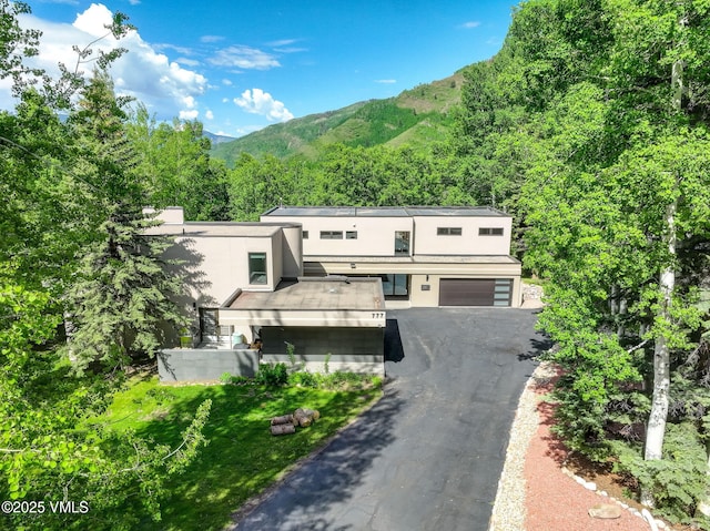 777 Potato Patch Dr Unit A, Vail, CO 81657 - view of front facade featuring asphalt driveway, stucco siding, a mountain view, a forest view, and an attached garage