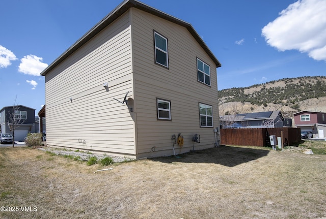 back of property featuring a mountain view and fence