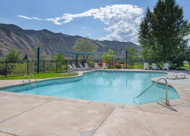 community pool featuring fence, a mountain view, and a patio
