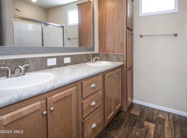 bathroom with a sink, double vanity, a shower with door, and wood finished floors
