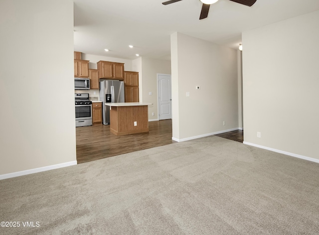 unfurnished living room with baseboards, ceiling fan, and carpet