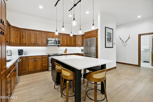295 Main St Unit R305, Edwards, CO 81632 - kitchen with appliances with stainless steel finishes, light countertops, a center island, light wood-style floors, and brown cabinets