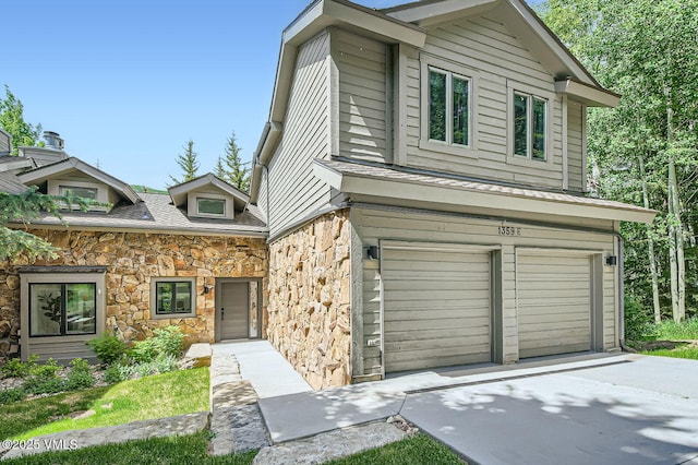 1359 Greenhill Ct Unit E, Vail, CO 81657 - view of front of property featuring stone siding, an attached garage, and concrete driveway