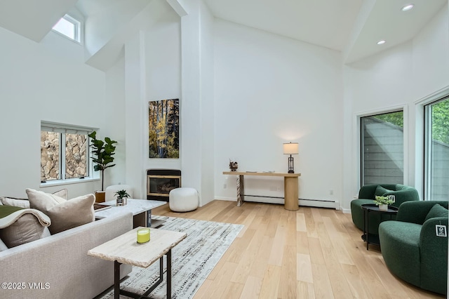 1359 Greenhill Ct Unit E, Vail, CO 81657 - living area with high vaulted ceiling, a baseboard radiator, a glass covered fireplace, recessed lighting, and light wood-type flooring