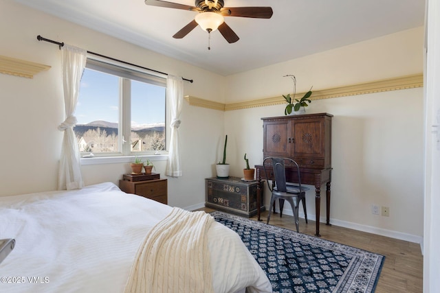 bedroom with a ceiling fan, a mountain view, wood finished floors, and baseboards