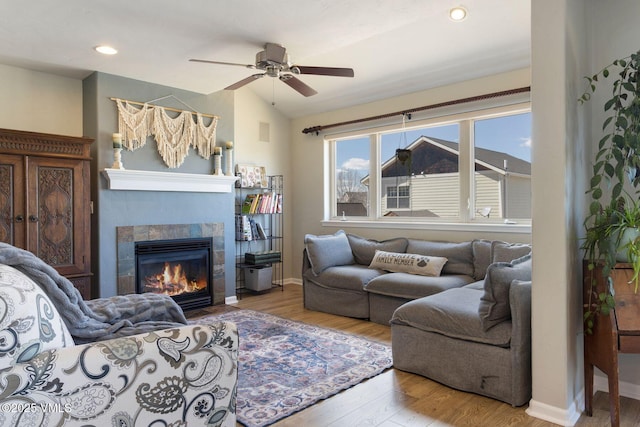 living room featuring wood finished floors, baseboards, lofted ceiling, a fireplace, and ceiling fan