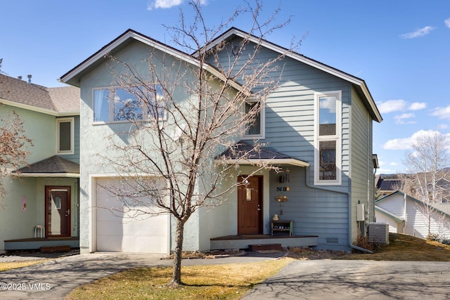 traditional-style home with central AC, a garage, driveway, and stucco siding