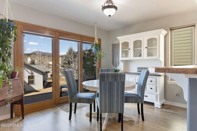 dining area with light wood finished floors, a mountain view, baseboards, and french doors