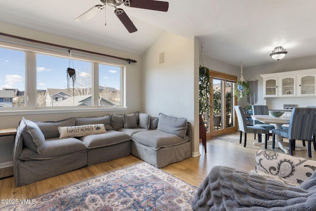 living room with vaulted ceiling, a ceiling fan, visible vents, and light wood finished floors