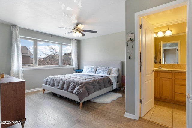 bedroom with a ceiling fan, baseboards, light wood finished floors, and a sink