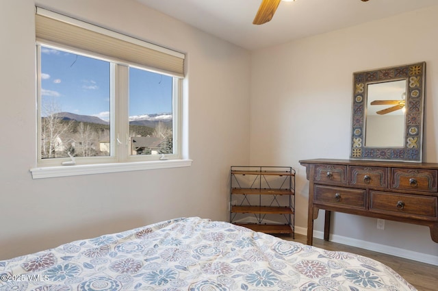 bedroom featuring a ceiling fan, a mountain view, wood finished floors, and baseboards