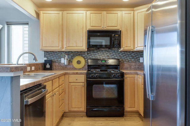 kitchen with a sink, black appliances, backsplash, and light brown cabinetry