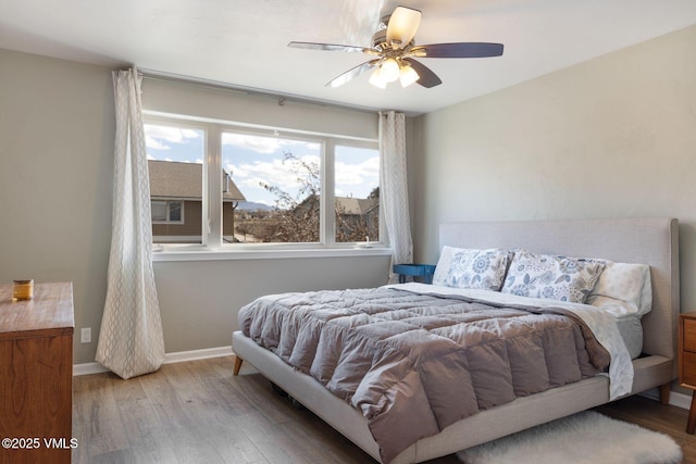 bedroom with ceiling fan, baseboards, and wood finished floors