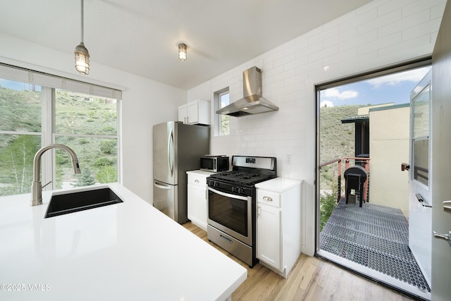 511 Metcalf Unit J30, Avon, CO 81620 - kitchen with appliances with stainless steel finishes, wall chimney exhaust hood, a sink, light countertops, and white cabinets