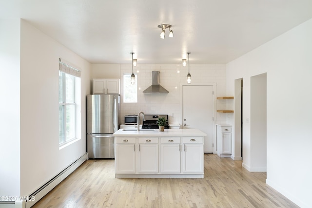 511 Metcalf Unit J30, Avon, CO 81620 - kitchen with freestanding refrigerator, wall chimney range hood, a baseboard radiator, backsplash, and a center island with sink