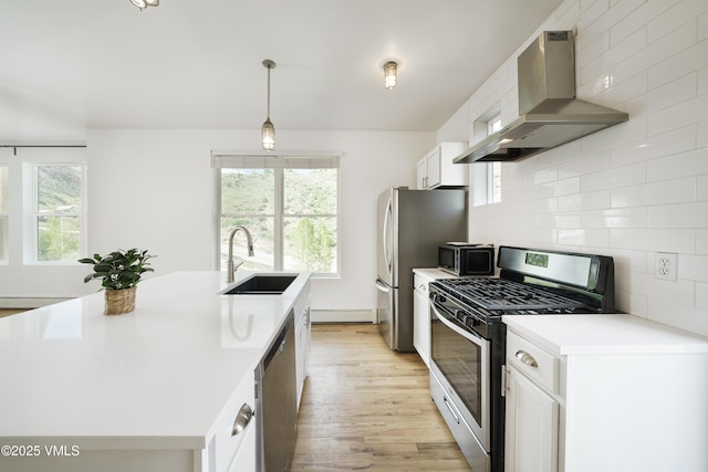 511 Metcalf Unit J30, Avon, CO 81620 - kitchen with stainless steel appliances, wall chimney range hood, a sink, light wood-type flooring, and an island with sink
