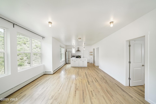 511 Metcalf Unit J30, Avon, CO 81620 - unfurnished living room featuring baseboard heating, light wood-style flooring, plenty of natural light, and baseboards