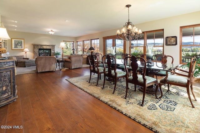 dining area with a fireplace, an inviting chandelier, and dark wood-style flooring