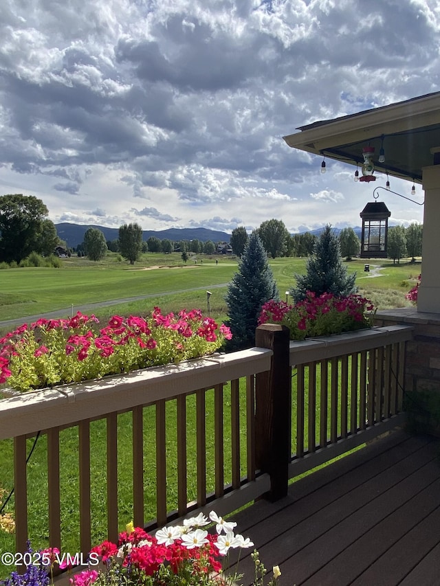 wooden terrace featuring a lawn and a mountain view