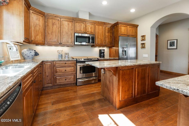 kitchen with dark wood finished floors, a center island, appliances with stainless steel finishes, and a sink