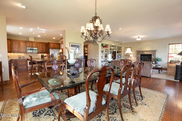 dining space with a high end fireplace, built in shelves, a chandelier, recessed lighting, and wood-type flooring