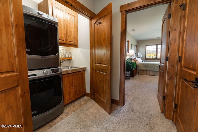 washroom with baseboards, light carpet, cabinet space, stacked washer / drying machine, and a sink