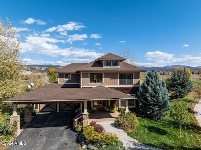 view of front of home with an attached carport, a mountain view, driveway, and roof with shingles