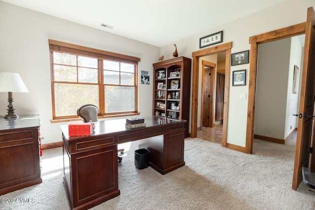 office space with baseboards, visible vents, and light carpet