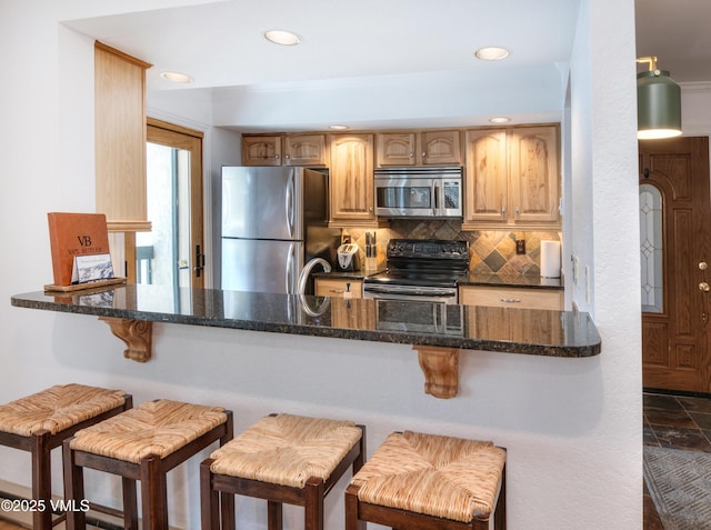 4479 Timber Falls Ct Unit 2001, Vail, CO 81657 - kitchen featuring stainless steel appliances, decorative backsplash, dark stone countertops, a kitchen bar, and recessed lighting