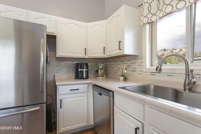 443 Porphyry Rd Unit F, Gypsum, CO 81637 - kitchen with appliances with stainless steel finishes, a sink, white cabinets, decorative backsplash, and light countertops