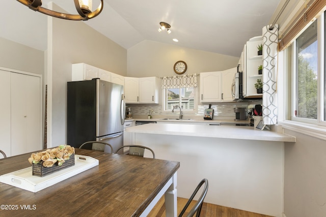 443 Porphyry Rd Unit F, Gypsum, CO 81637 - kitchen featuring stainless steel appliances, a peninsula, a sink, lofted ceiling, and white cabinets